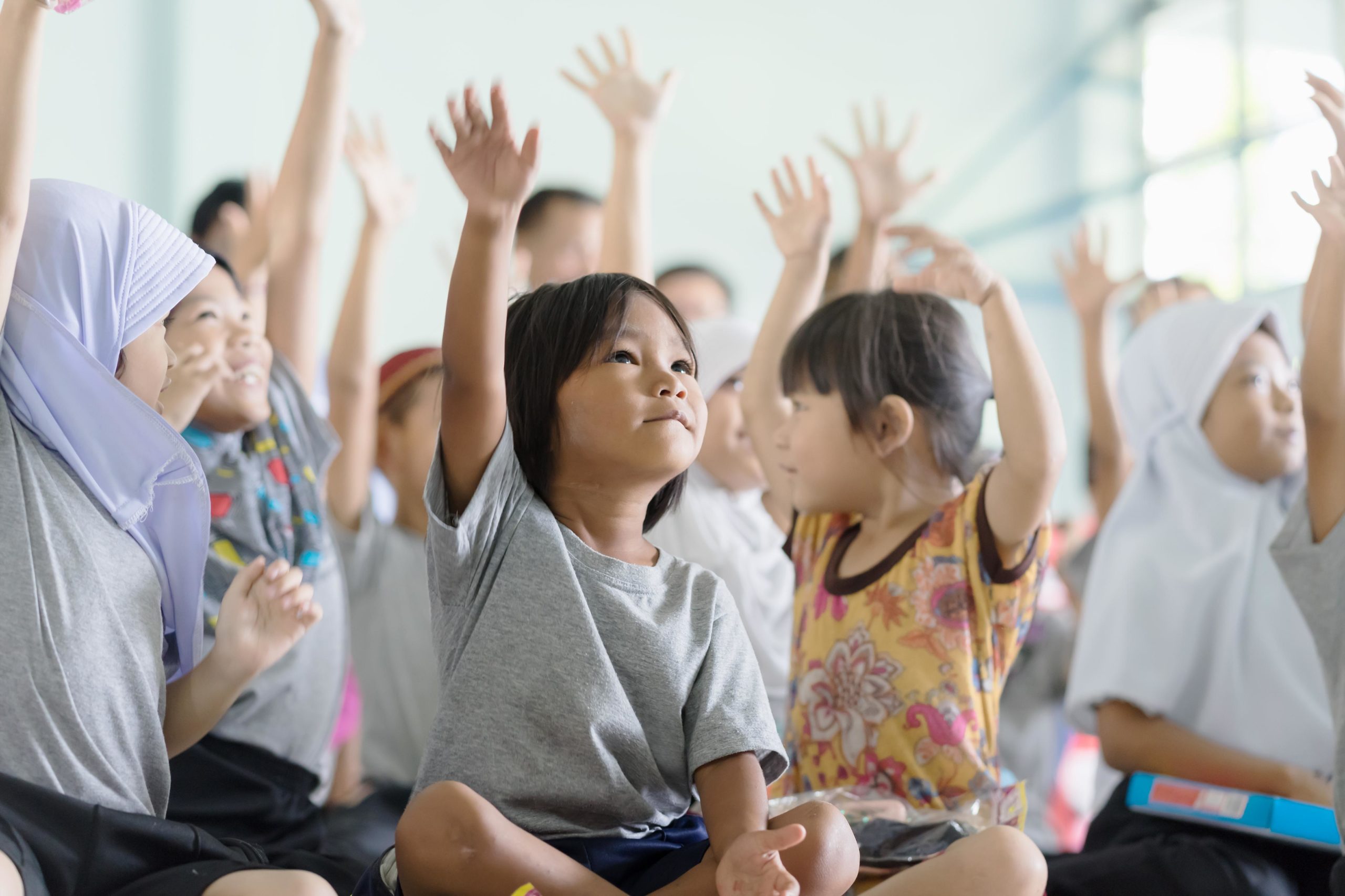 children raising their hands at school