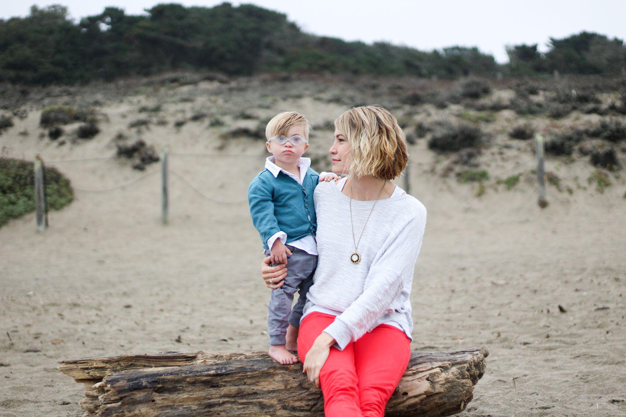 mom sitting on a tree stump with a child with down syndrome - raising a child with down syndrome