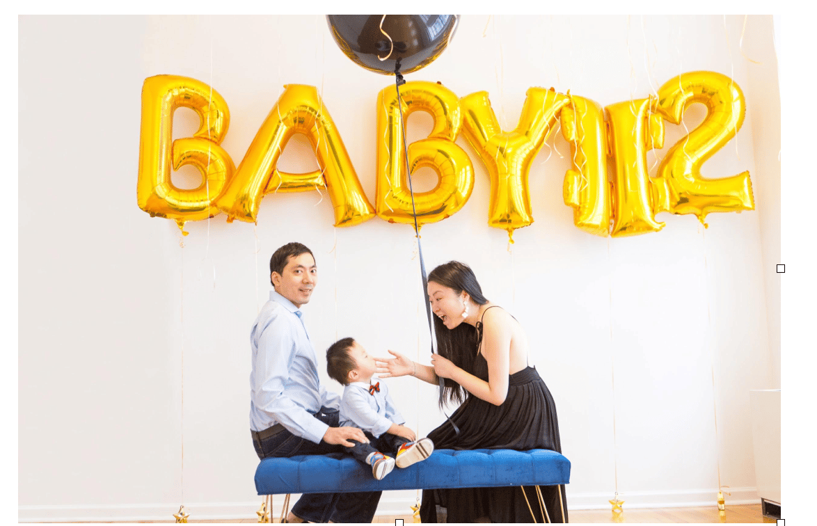 parents and baby behind balloons that read 