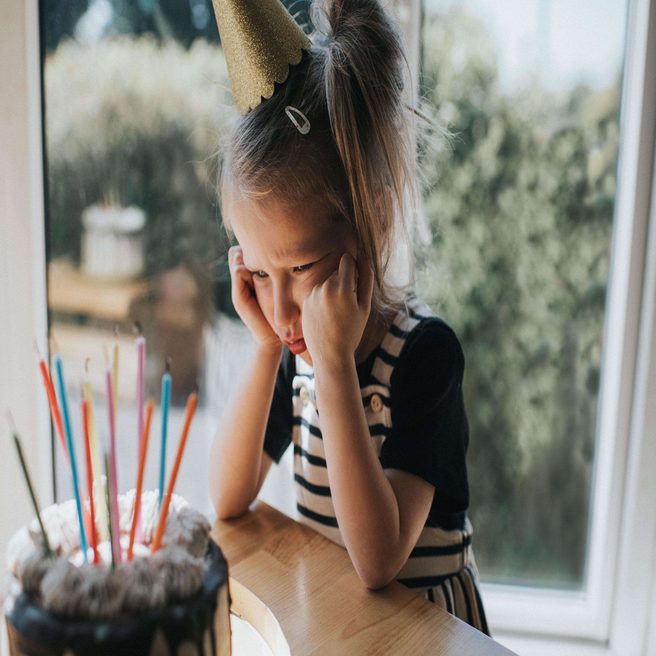 birthday spankings: young girl sad at her birthday party in front of cake