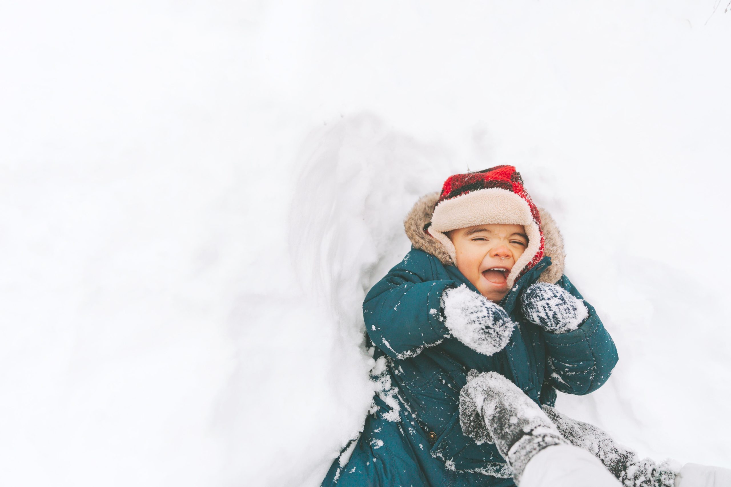 baby laughing and laying down in the snow- winter baby names