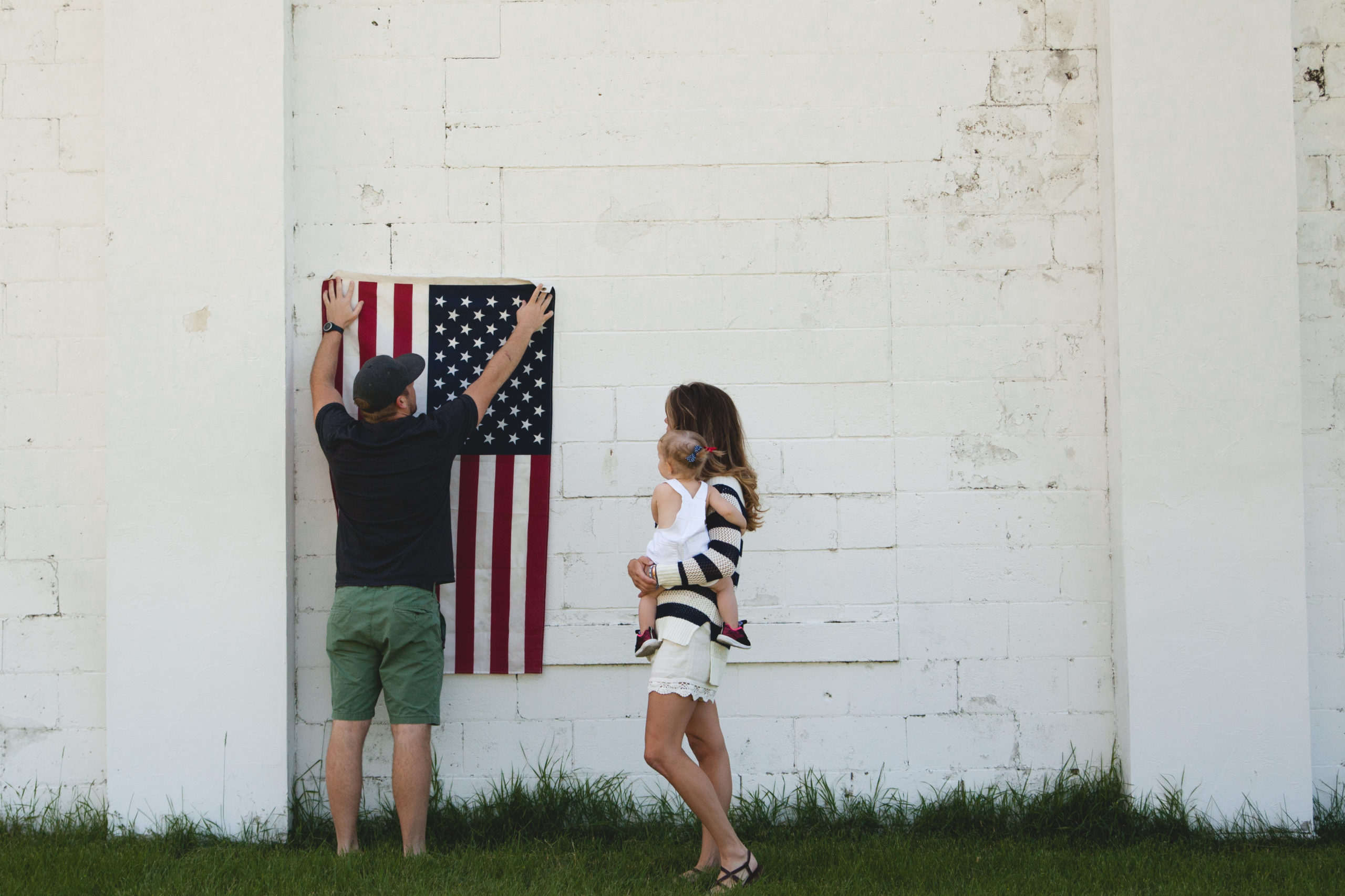 mom holding a child while dad hangs up flag