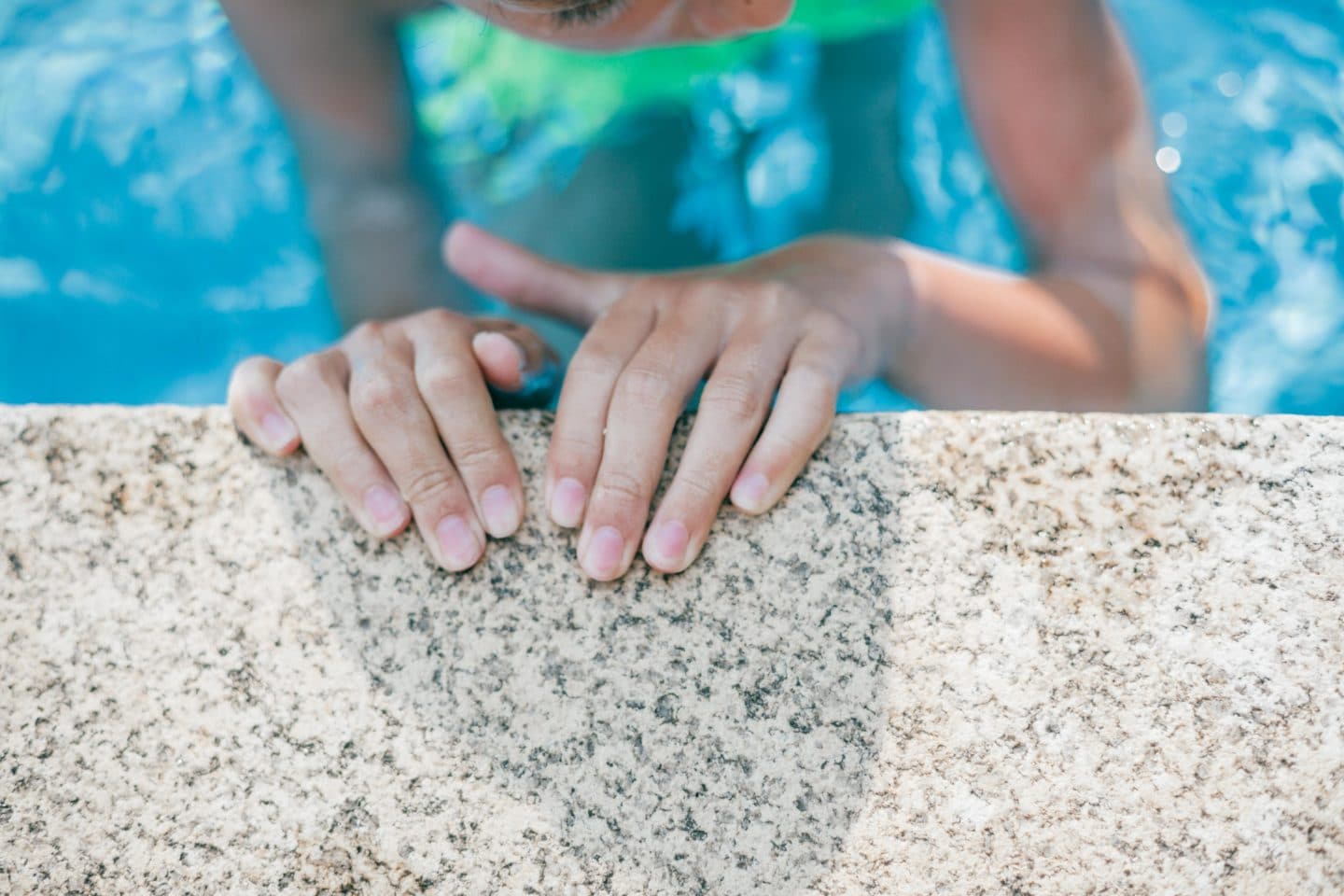little girls hands on the edge of a pool