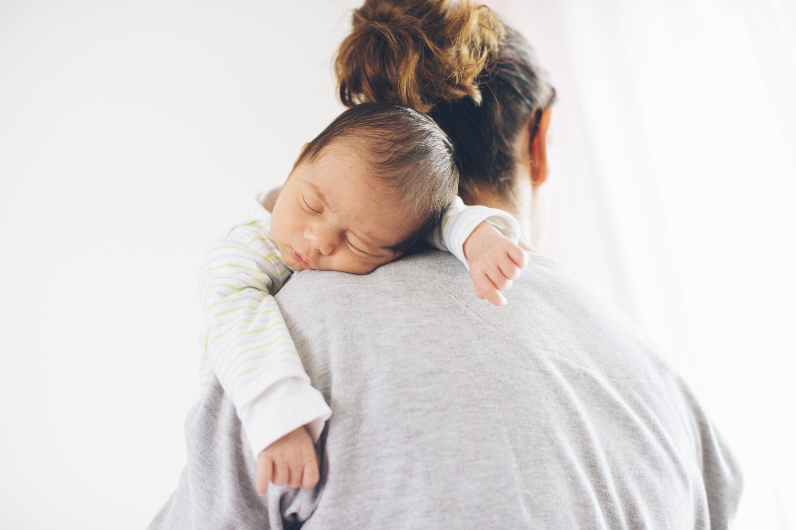 newborn baby sleeping on moms shoulder