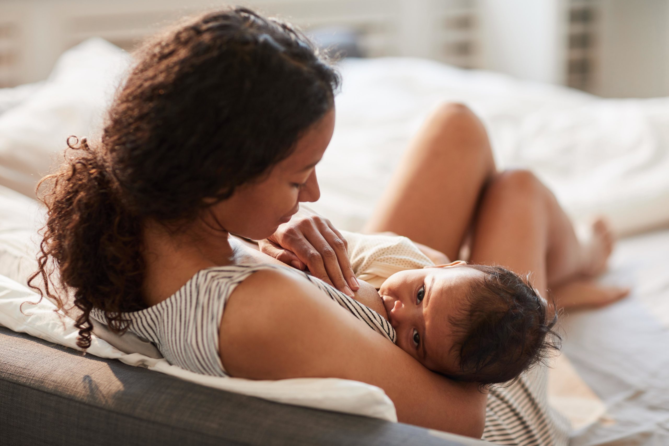 mom breastfeeding baby on bed