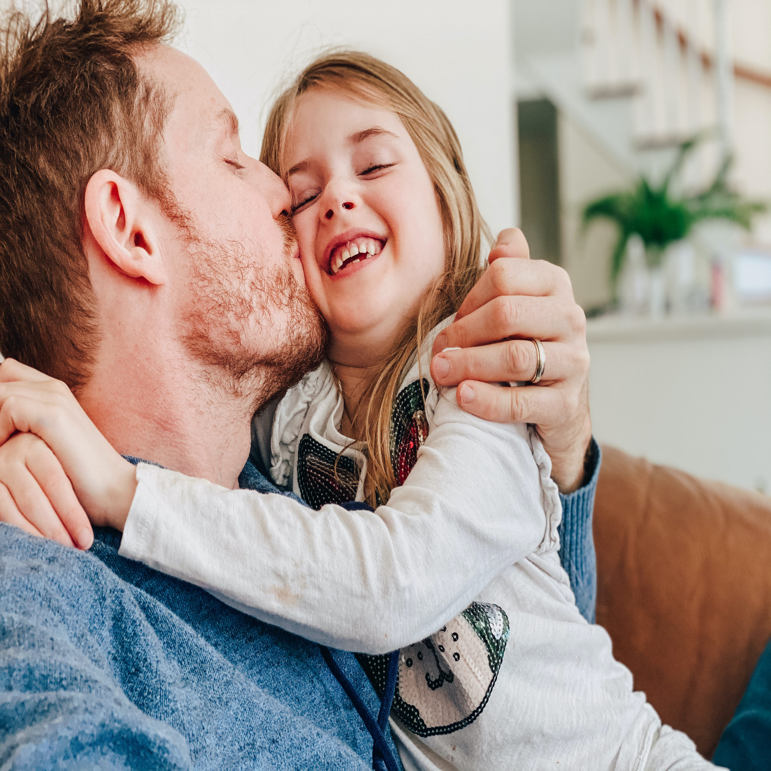 dad kissing daughter on the cheek