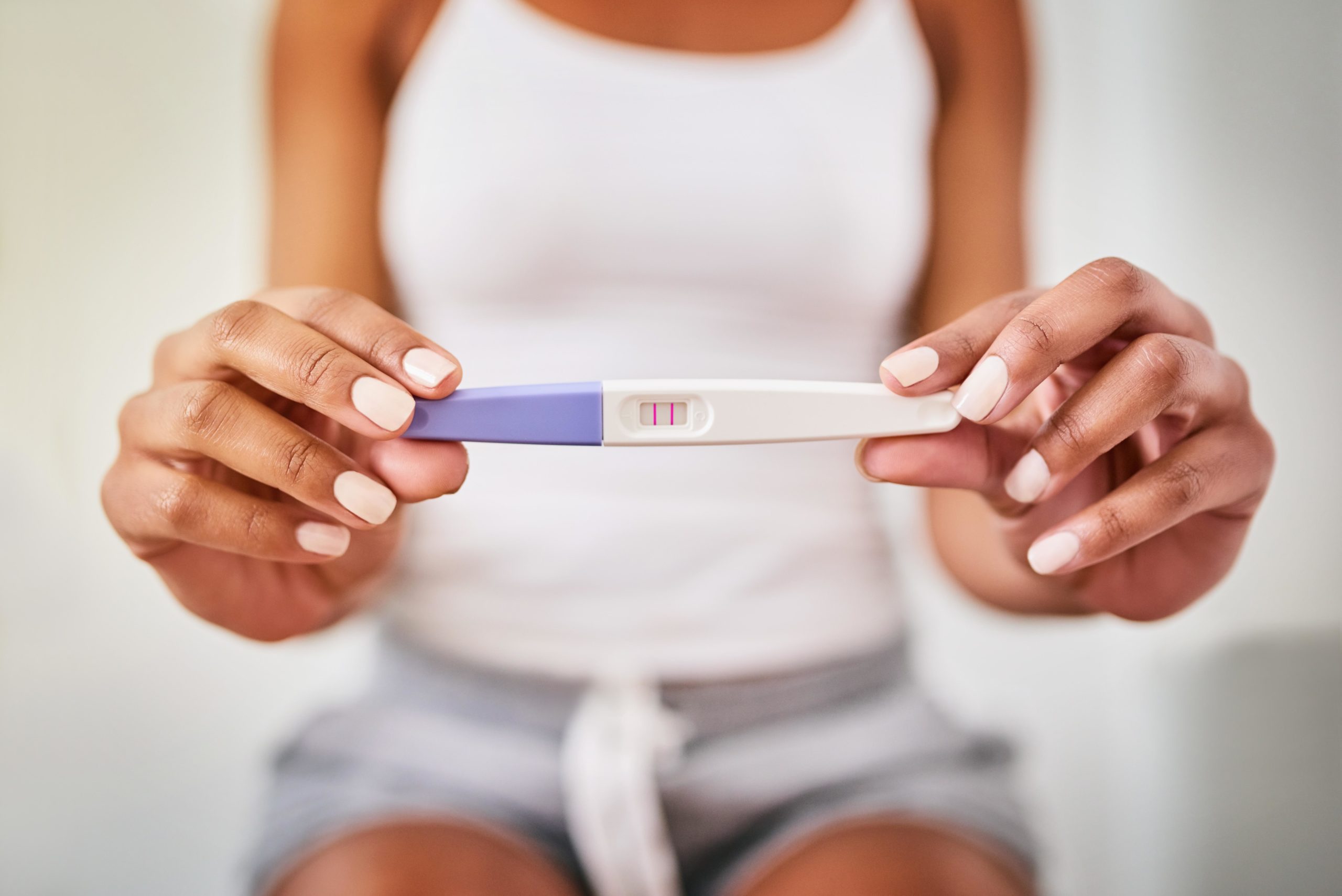 woman holding a positive pregnancy test - but what causes a false positive pregnancy test