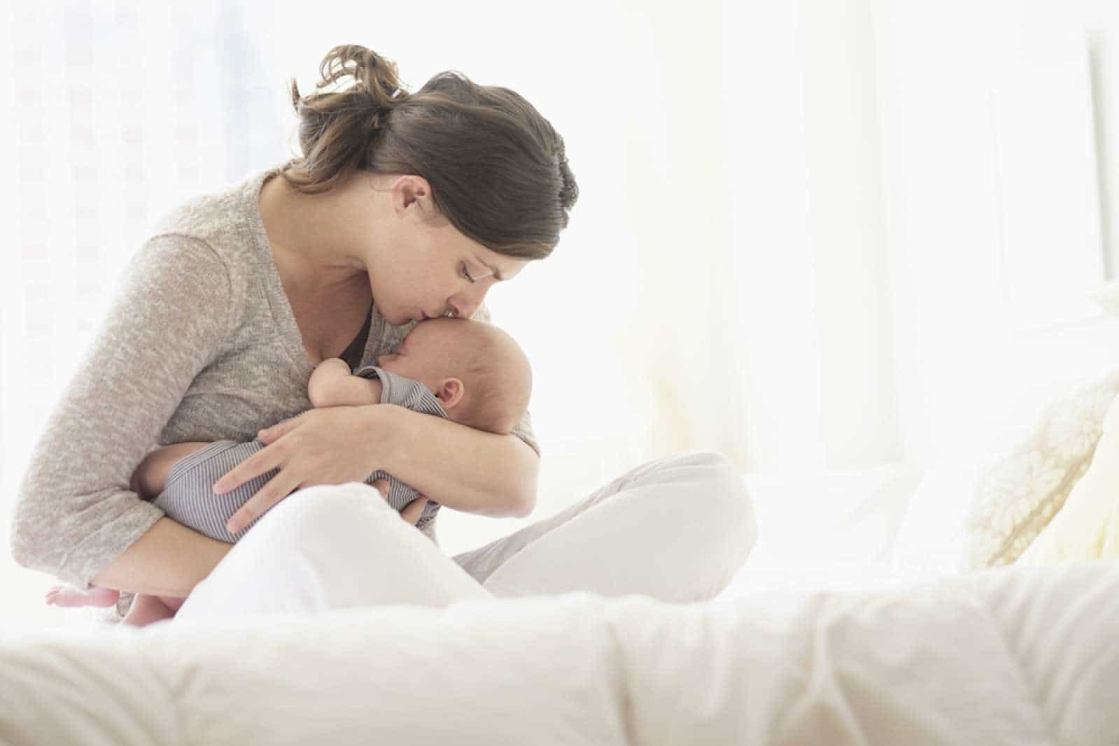 mom kissing newborn on the forehead