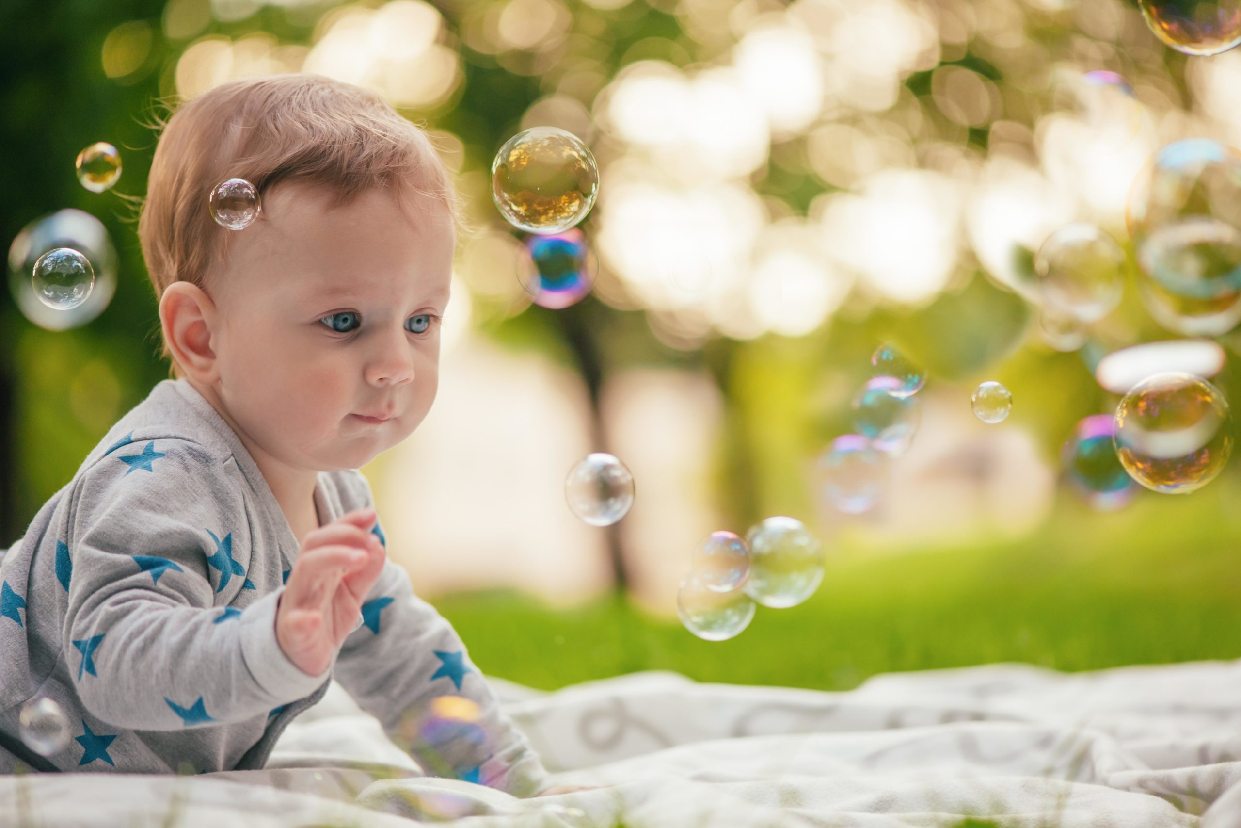 baby playing with bubbles outside