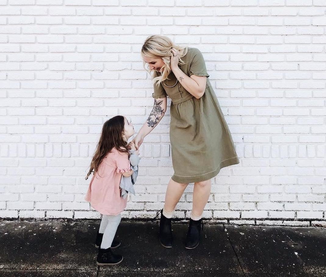 mom holding daughters hand against a brick wall