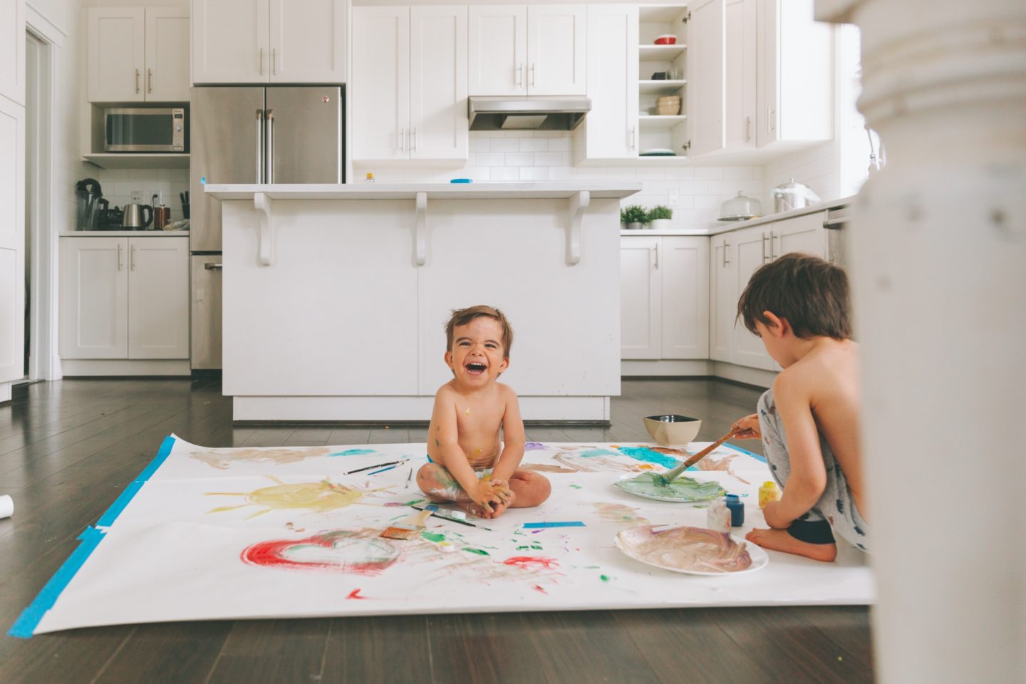siblings playing on the kitchen floor