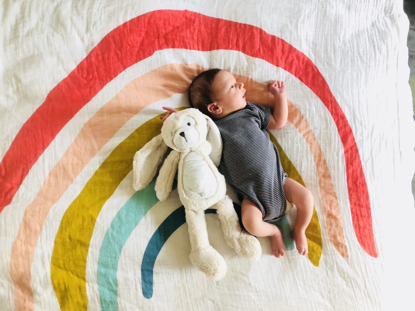 baby laying on a rainbow blanket