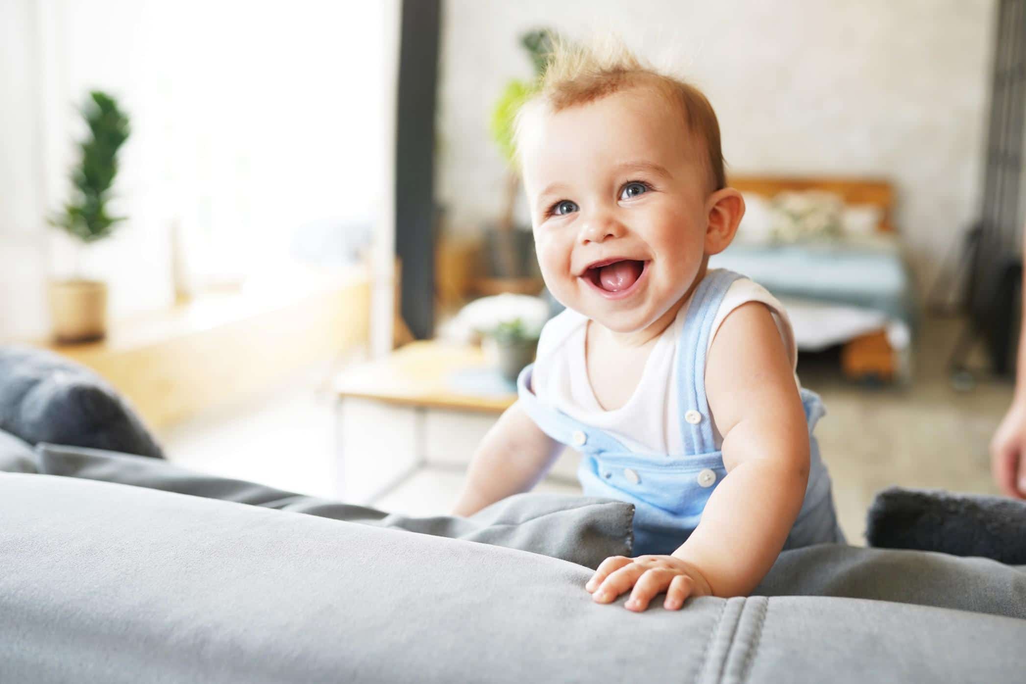 happy baby standing up on the back of a couch