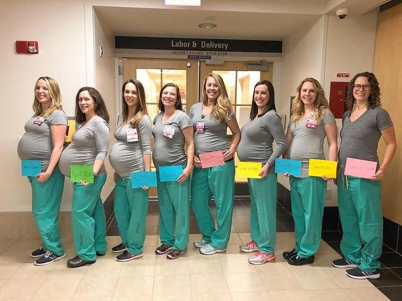 pregnant nurses standing together holding their due dates in front of them