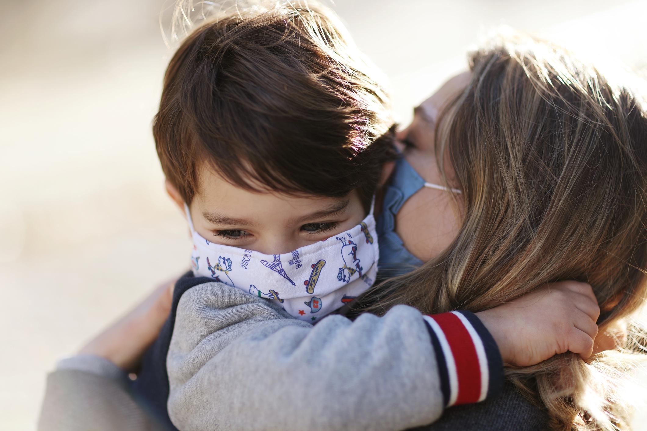 mom and son wearing masks and hugging