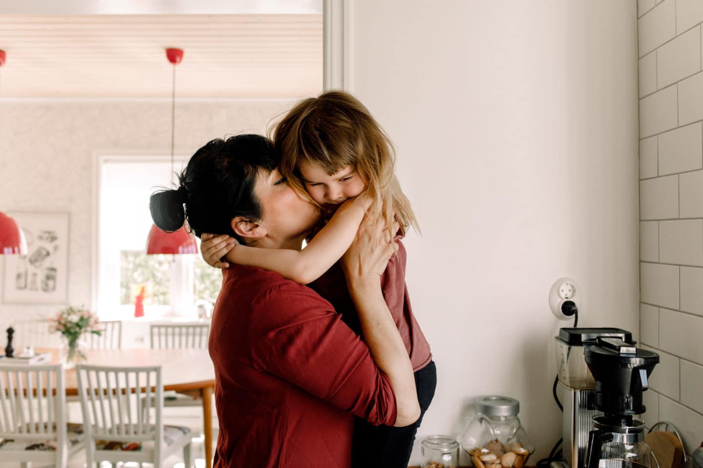 mom holding daughter and kissing her cheek