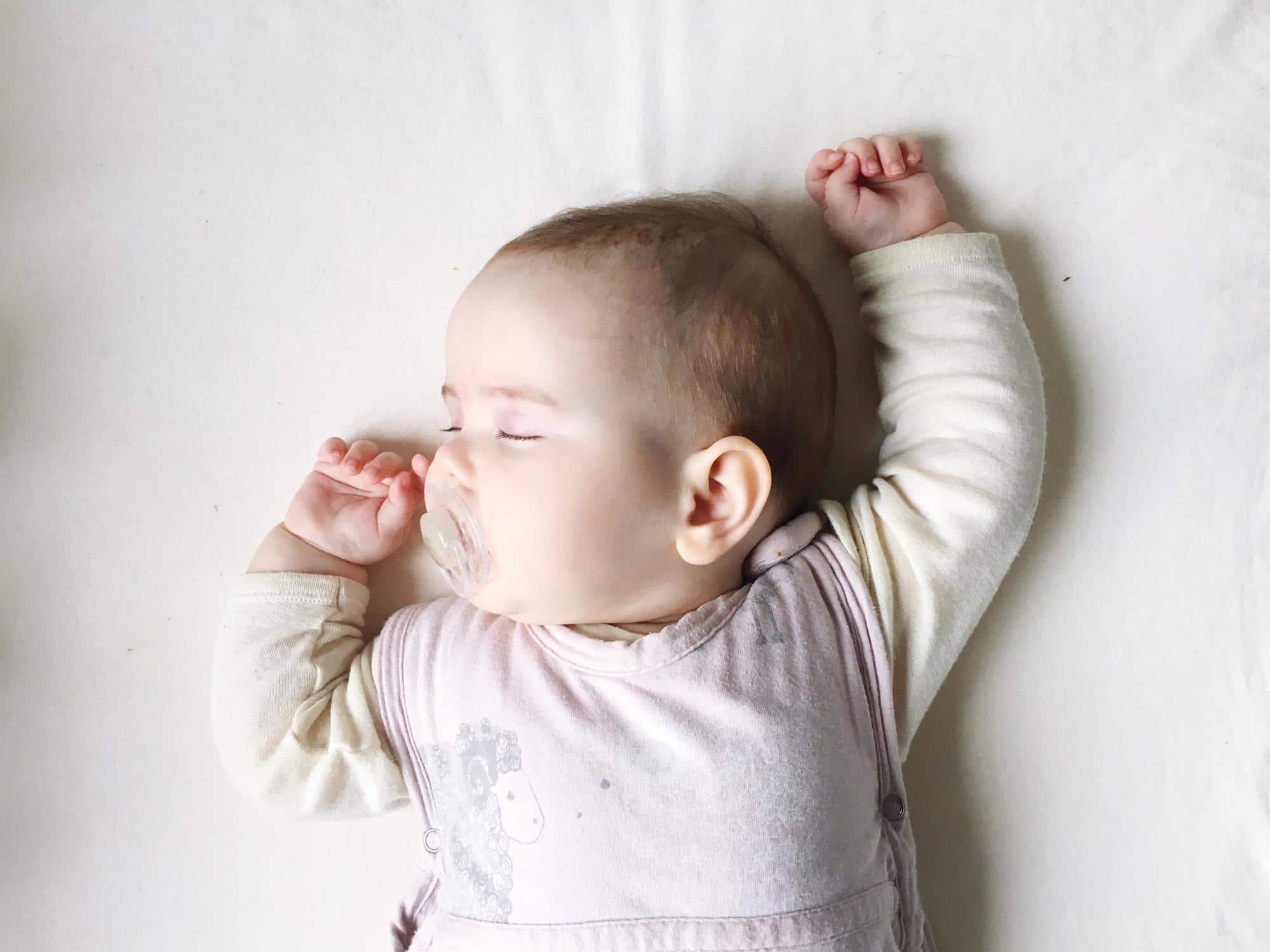 seven-week-old baby sleeping with arms above its head