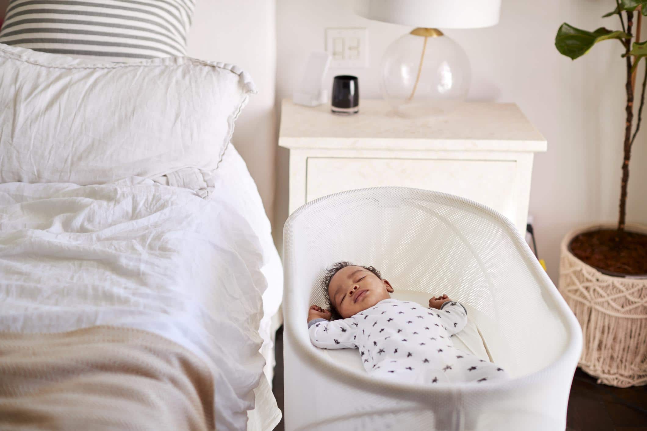 baby sleeping in a bassinet close to a bed