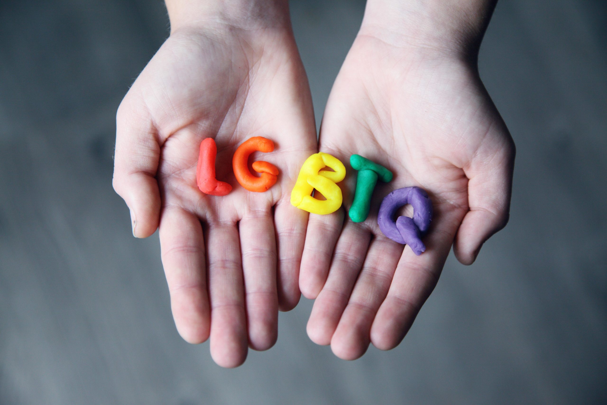 hands holding LGBTQ in clay