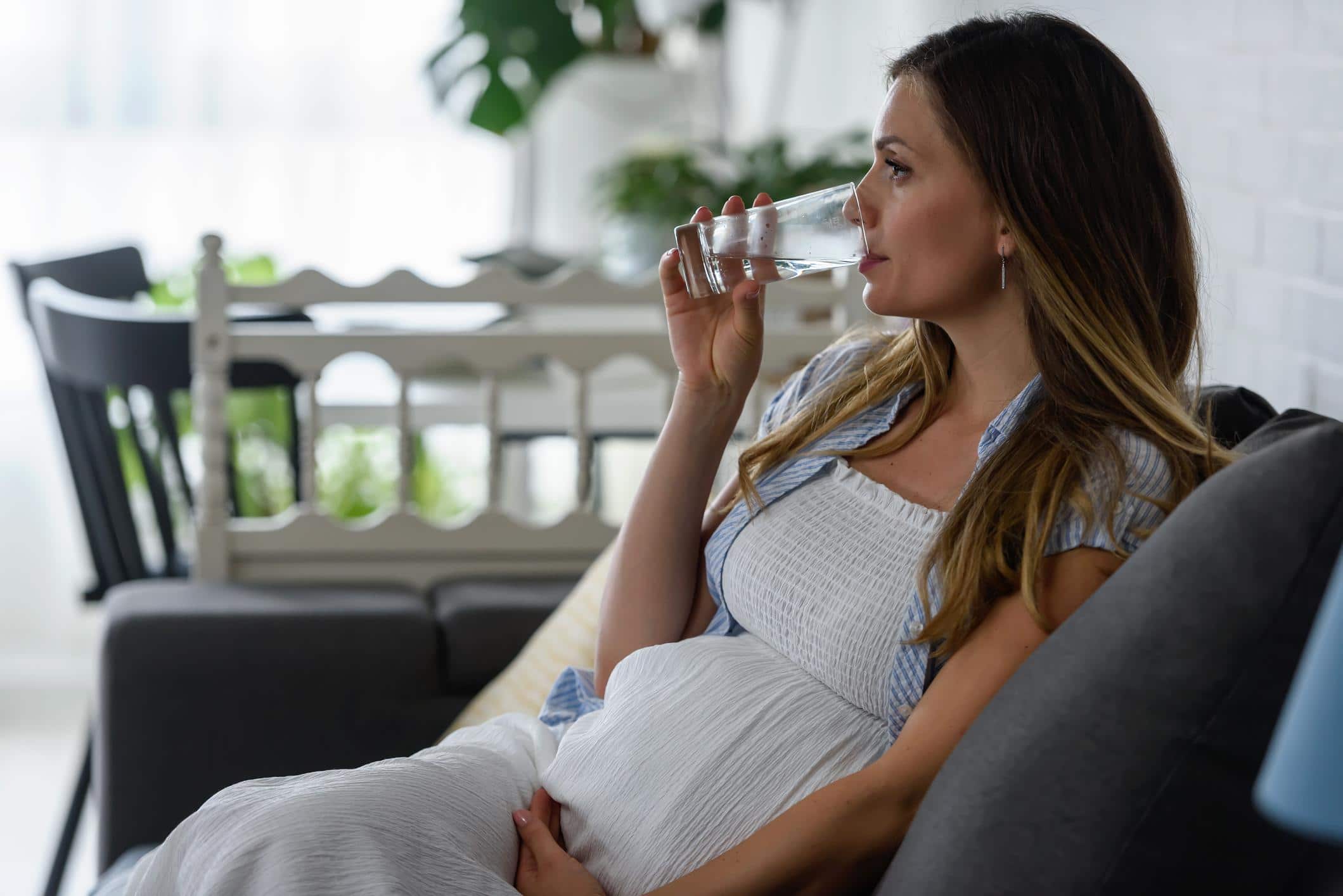 woman holding belly drinking water