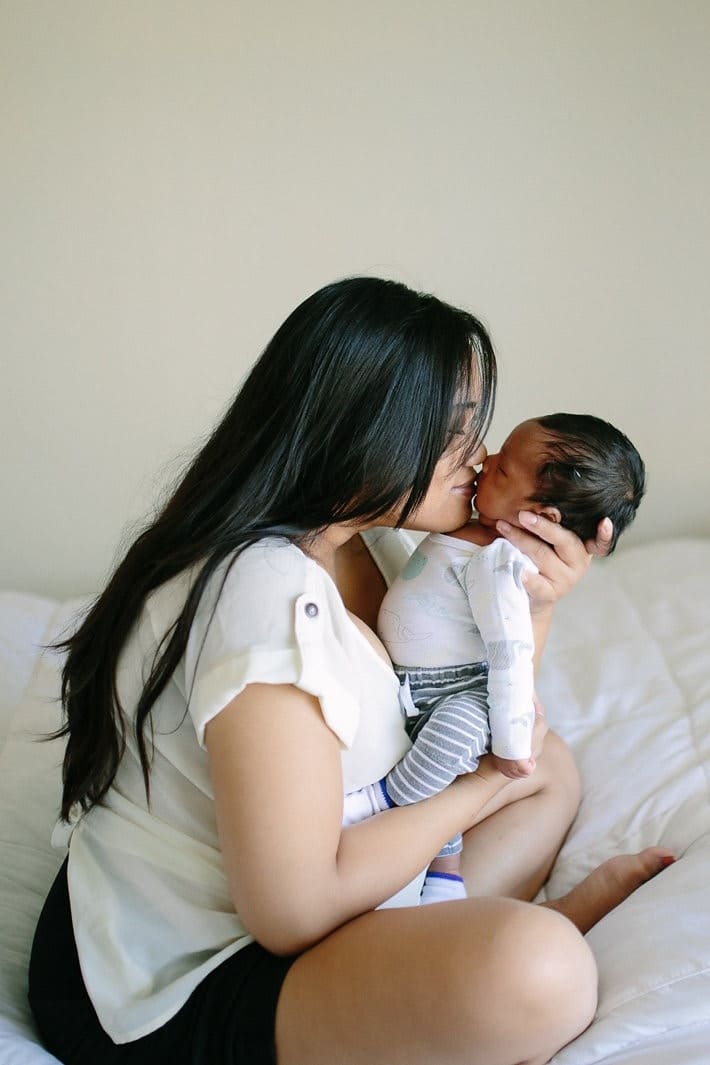 mom kissing newborn baby