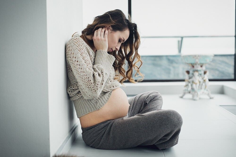 pregnant woman sitting on the floor looking at her belly