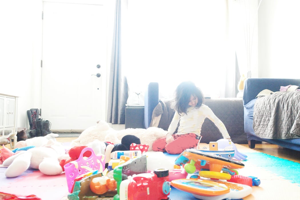 child sitting on the living room floor with toys all about- stop apologizing for a messy house