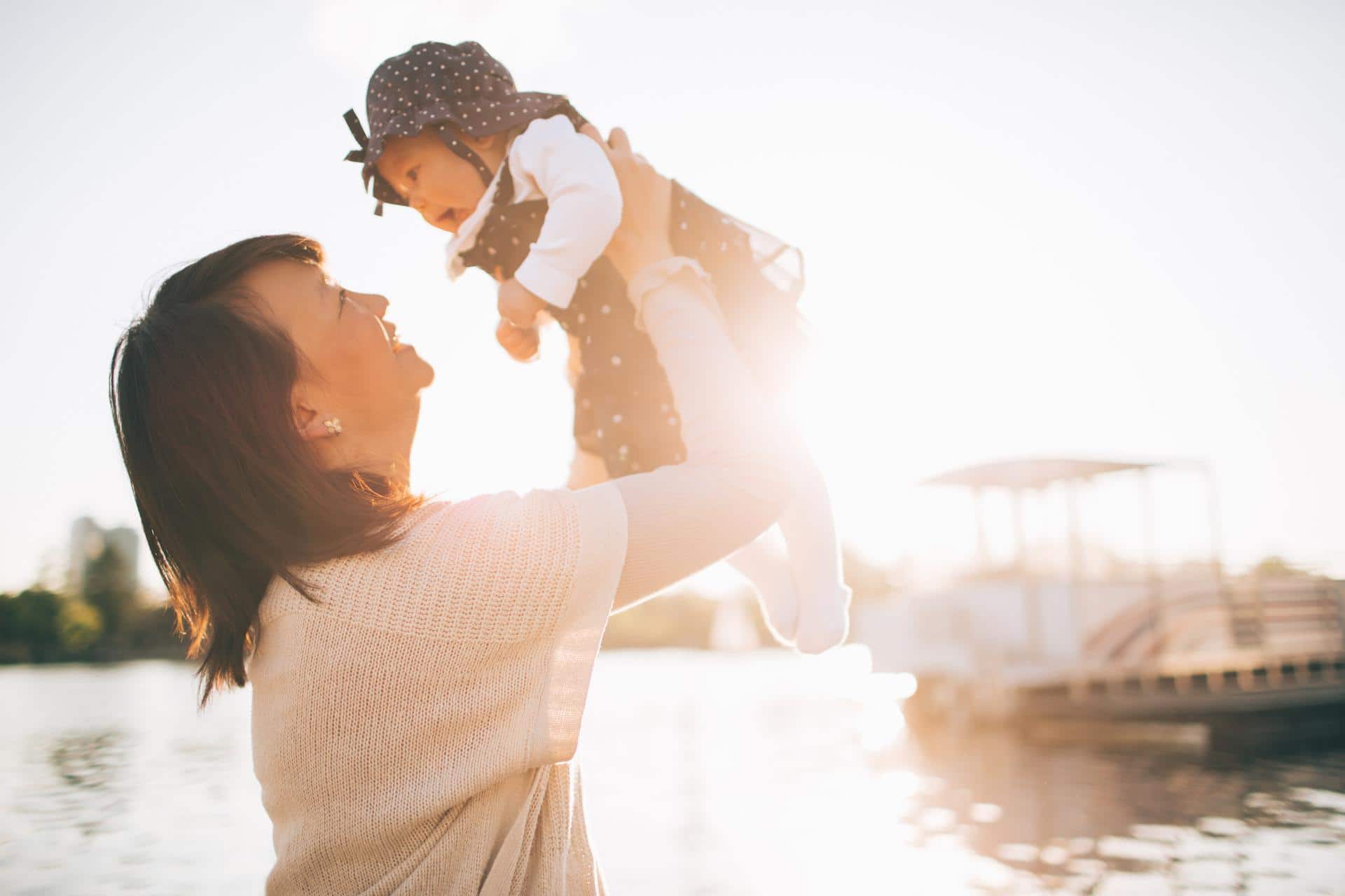 mom holding baby up in the sky