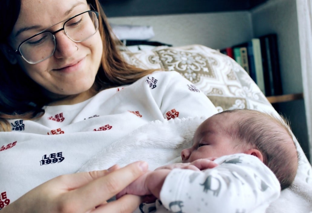 mom holding newborn baby laying down