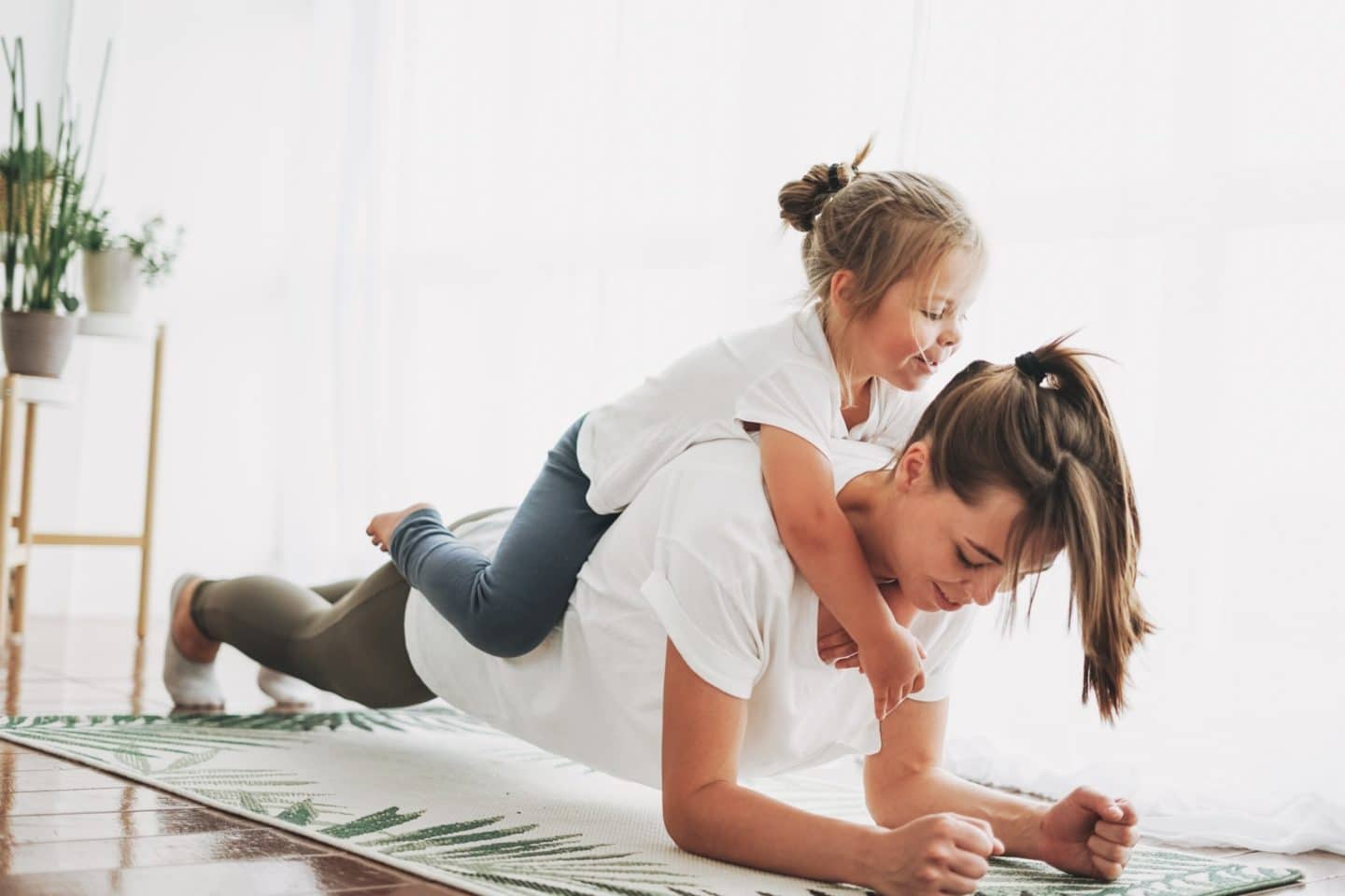 mom doing a plank with daughter on her back