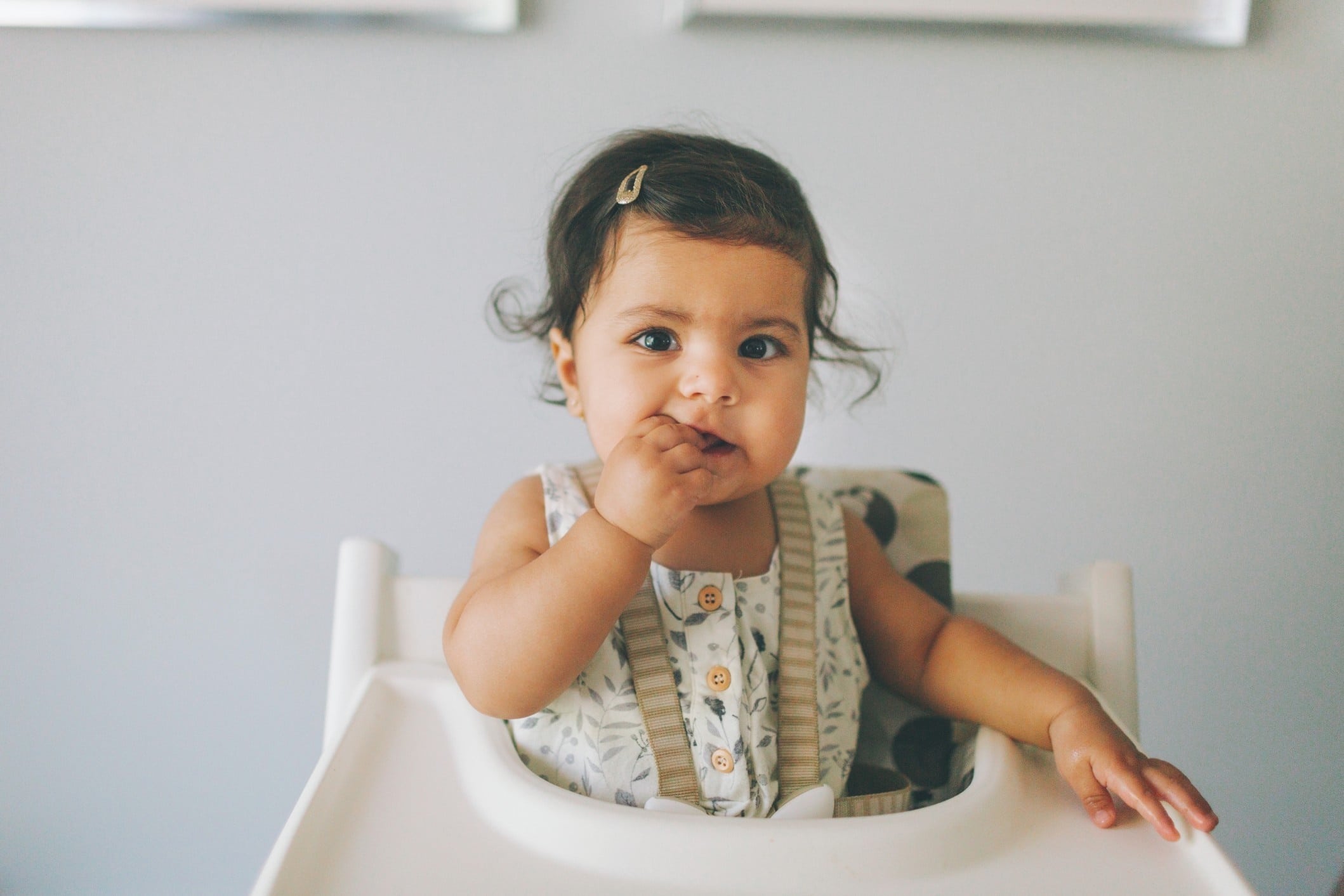 little girl eating food in a high chair