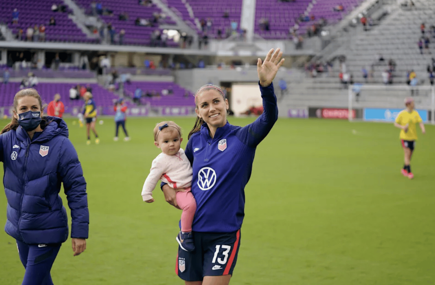Olympic soccer athlete holding her baby on the field