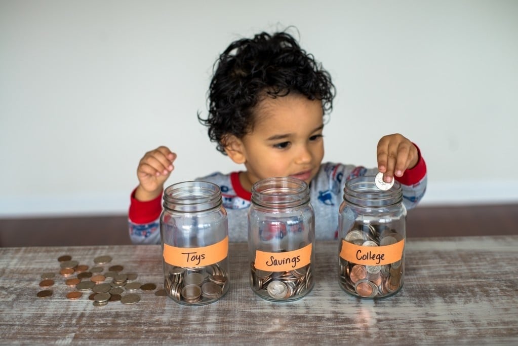 child playing with money and jars