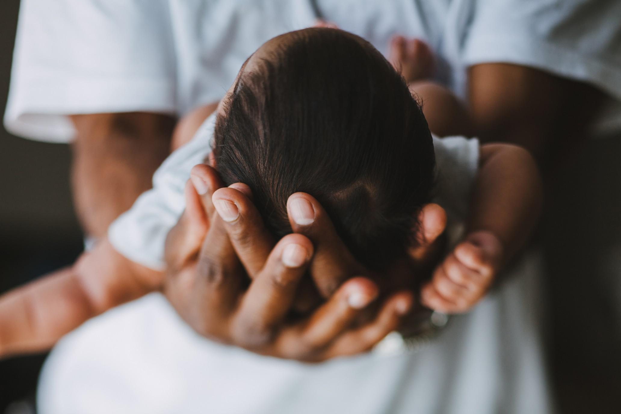 mom holding baby's head in her palms, celebrating 1-month milestones