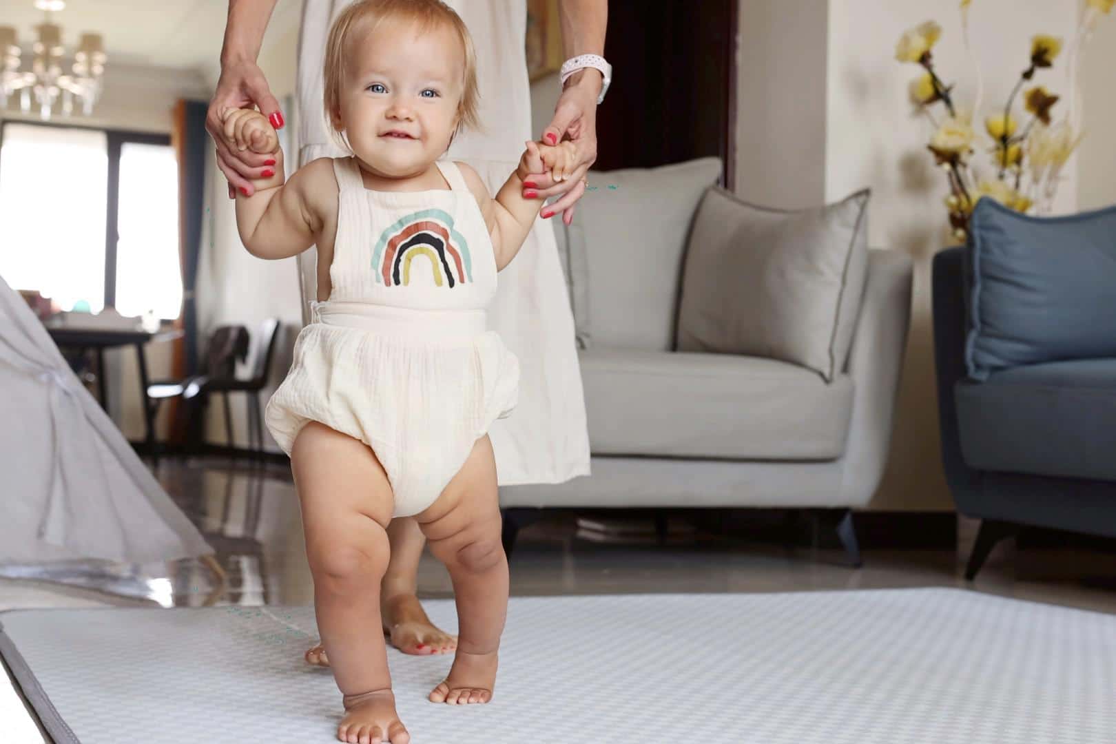 baby walking with help, one of the more common 12-month milestones