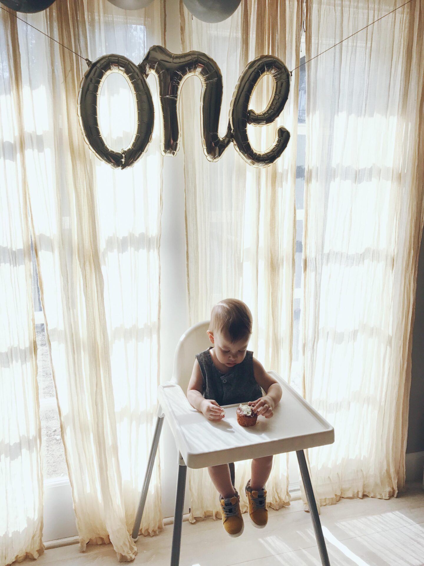 baby with birthday balloons over his head