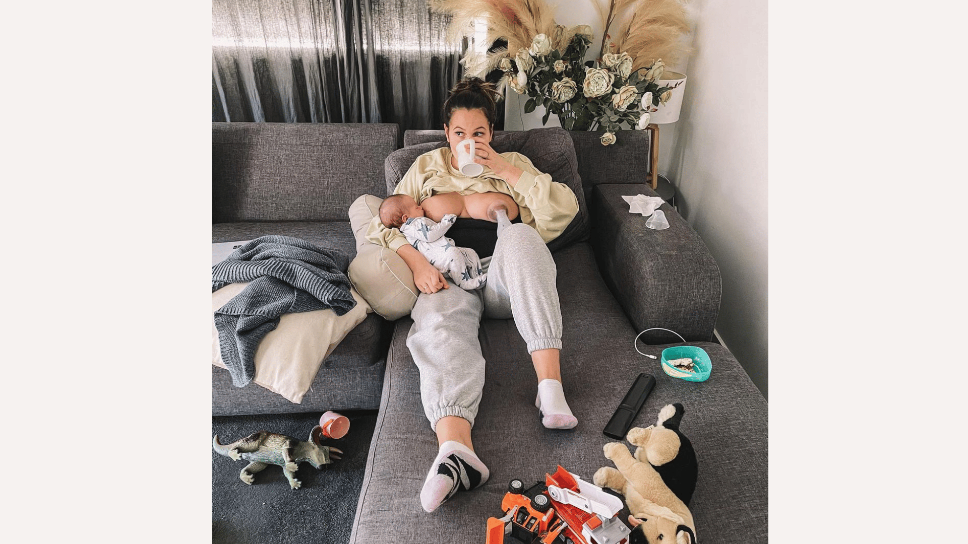 mom holding a baby on the couch drinking coffee