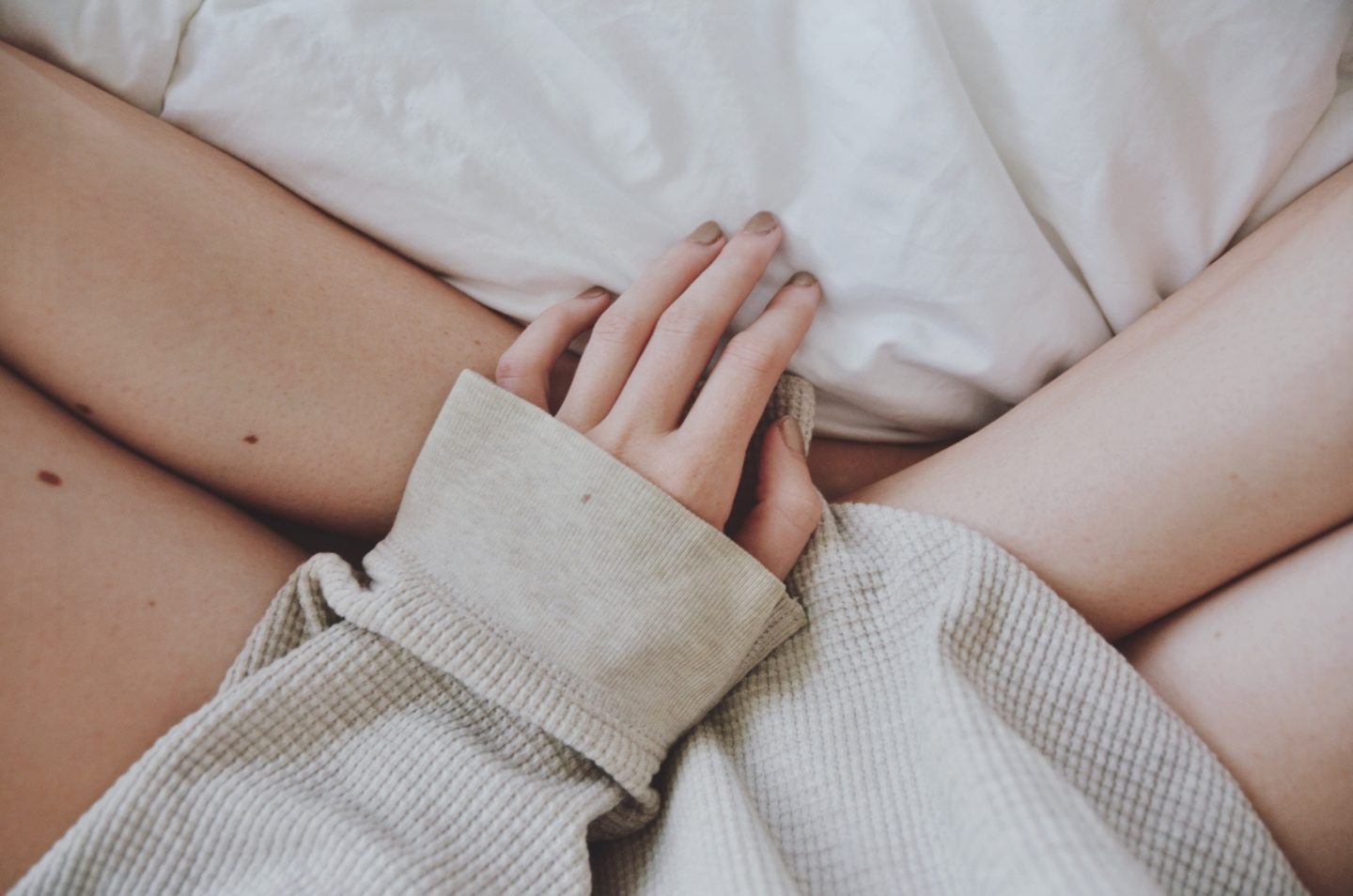 women sitting in bed with hands on leg