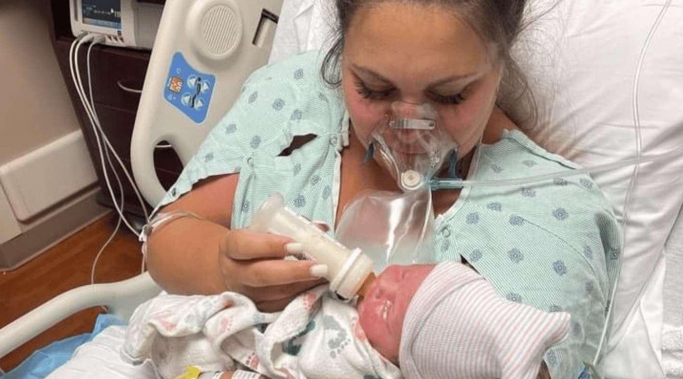 mom on oxygen giving bottle to newborn baby