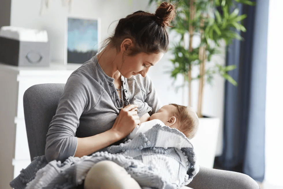 woman nursing baby while wearing pajamas