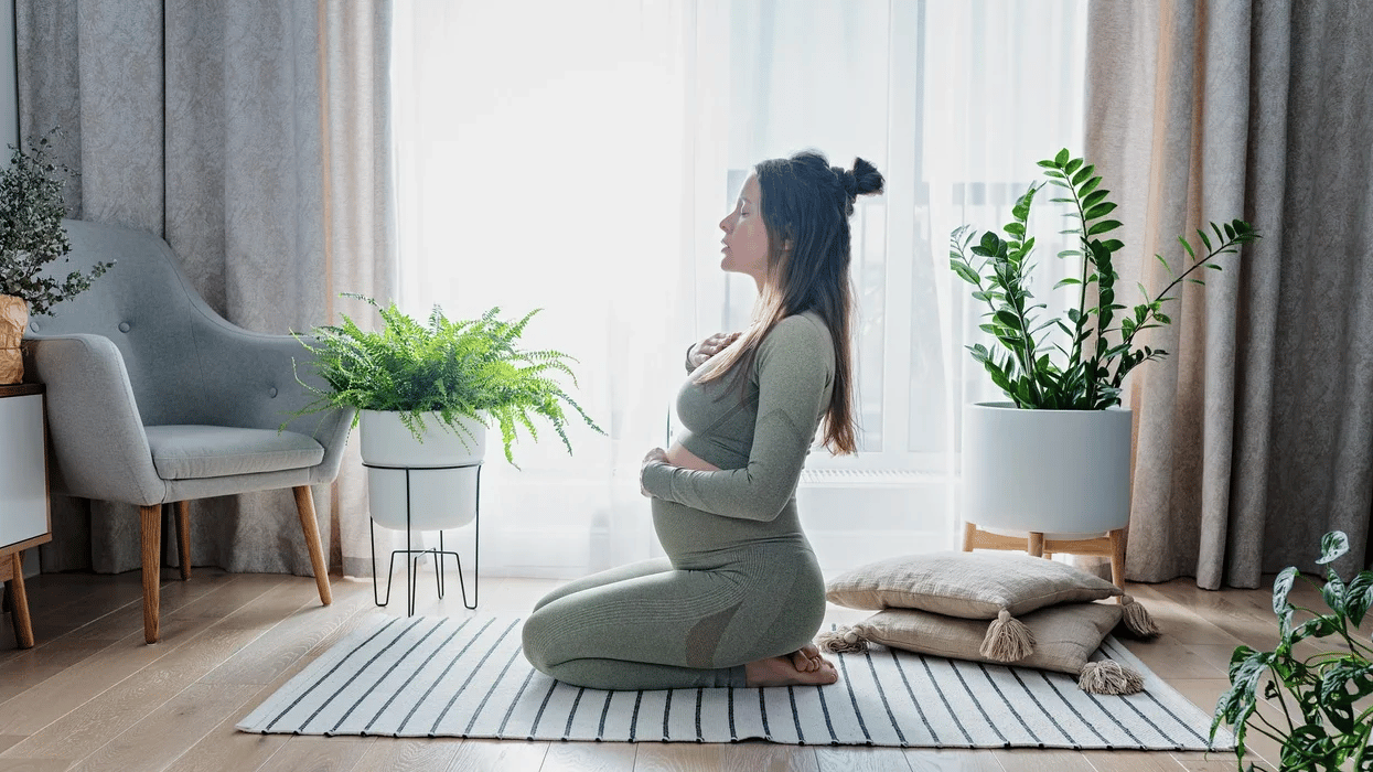 pregnant woman exercising yoga Motherly