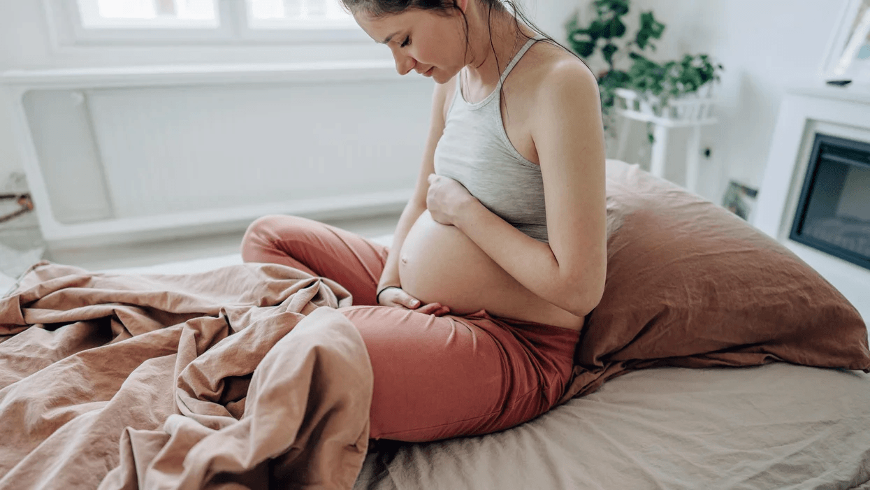 pregnant woman on a bed holding her belly 1