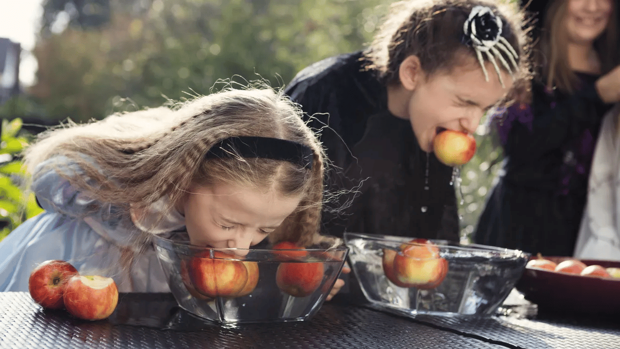 two girls bobbing for apples - kids Halloween games ideas