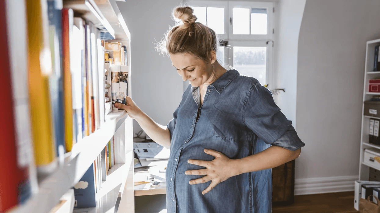 woman holding pregnant belly smiling Motherly