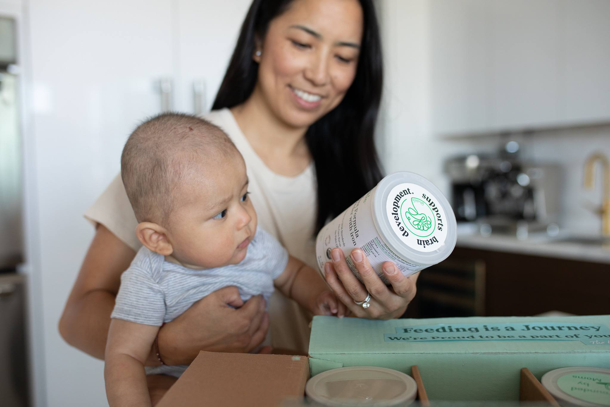 mom holding baby and a bottle of Bobbie Baby formula