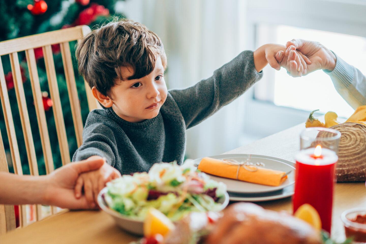 little boy holding hands at dinner - how to celebrate thanksgiving respectfully