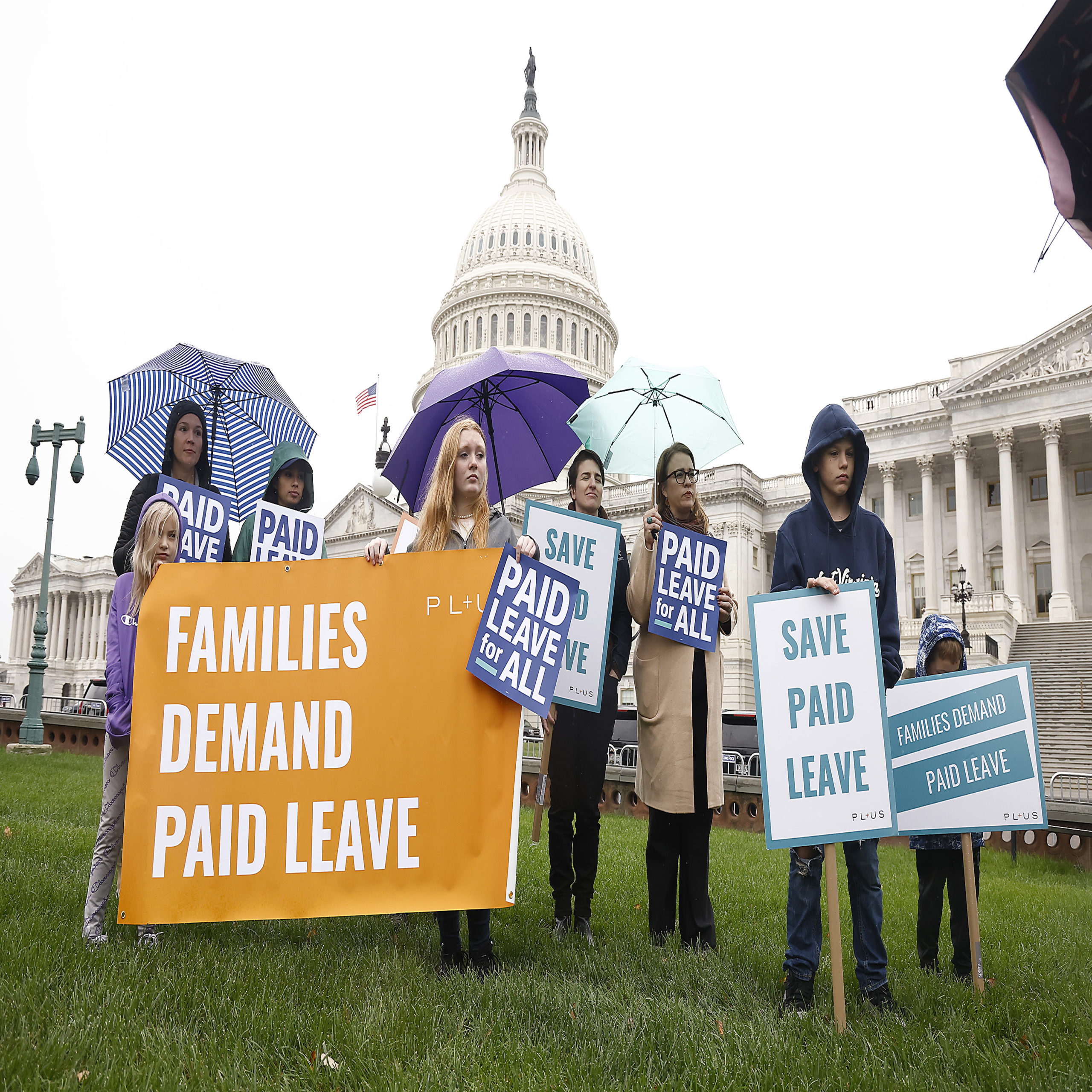 women-holding-signs-in-front-of-captial-building-about-paid-leave