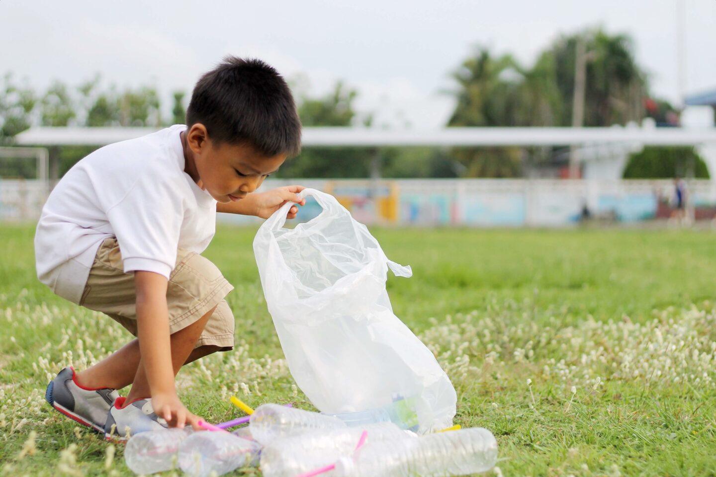 child picking up empty water bottles from grass-volunteering with kids