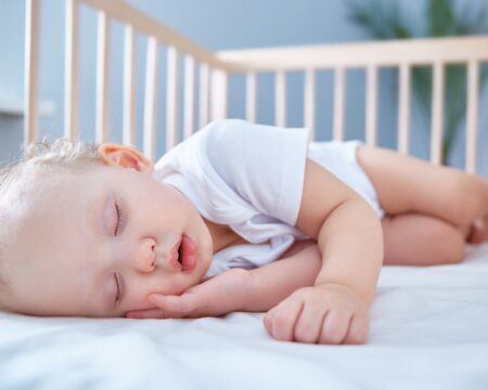 baby sleeps in her baby wooden crib for newborns a spacious bright room with a date palm tree in the t20 aa1WNv Motherly