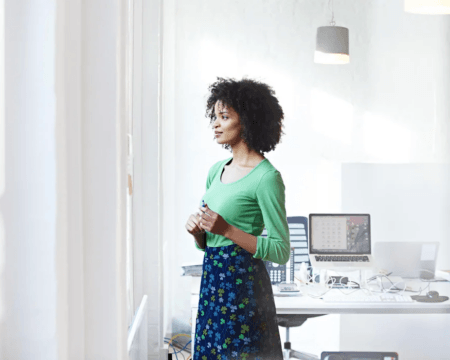 black woman in business office staring out window Motherly